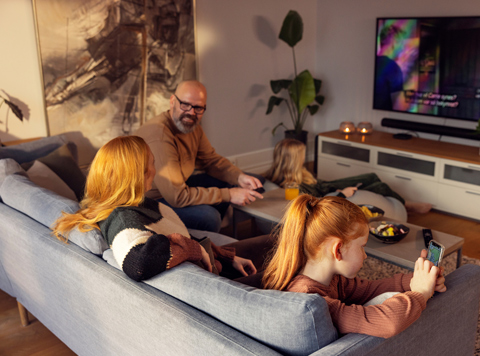 Familie ser på TV sammen i sofaen