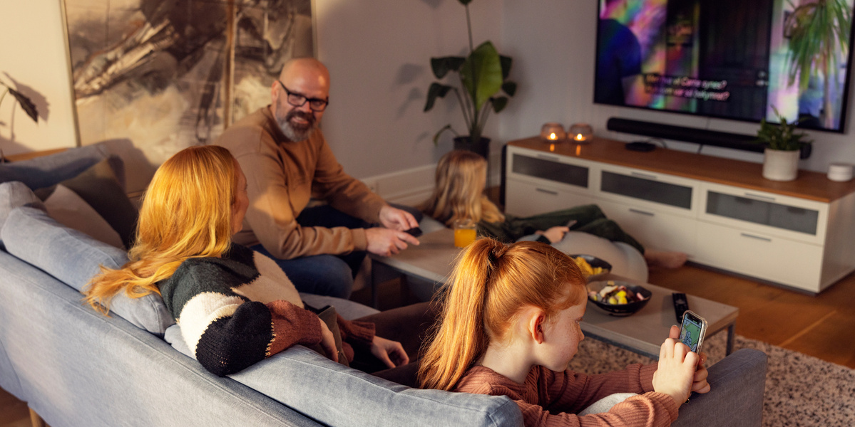 Familie ser på TV sammen i sofaen