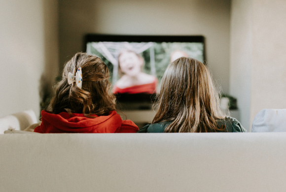 To søsken ser på TV i sofaen