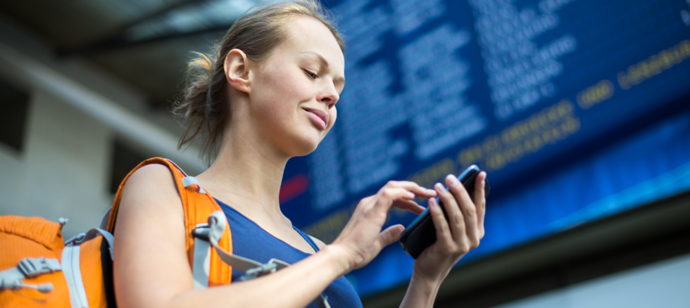 Ung jente på flyplass som surfer på internett på telefonen