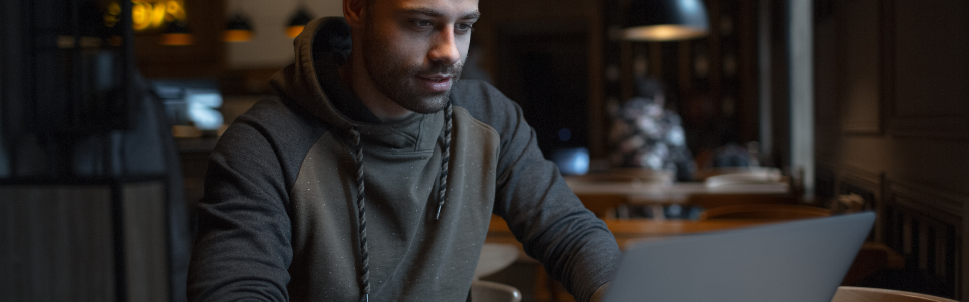 Young confident man using laptop in cafe