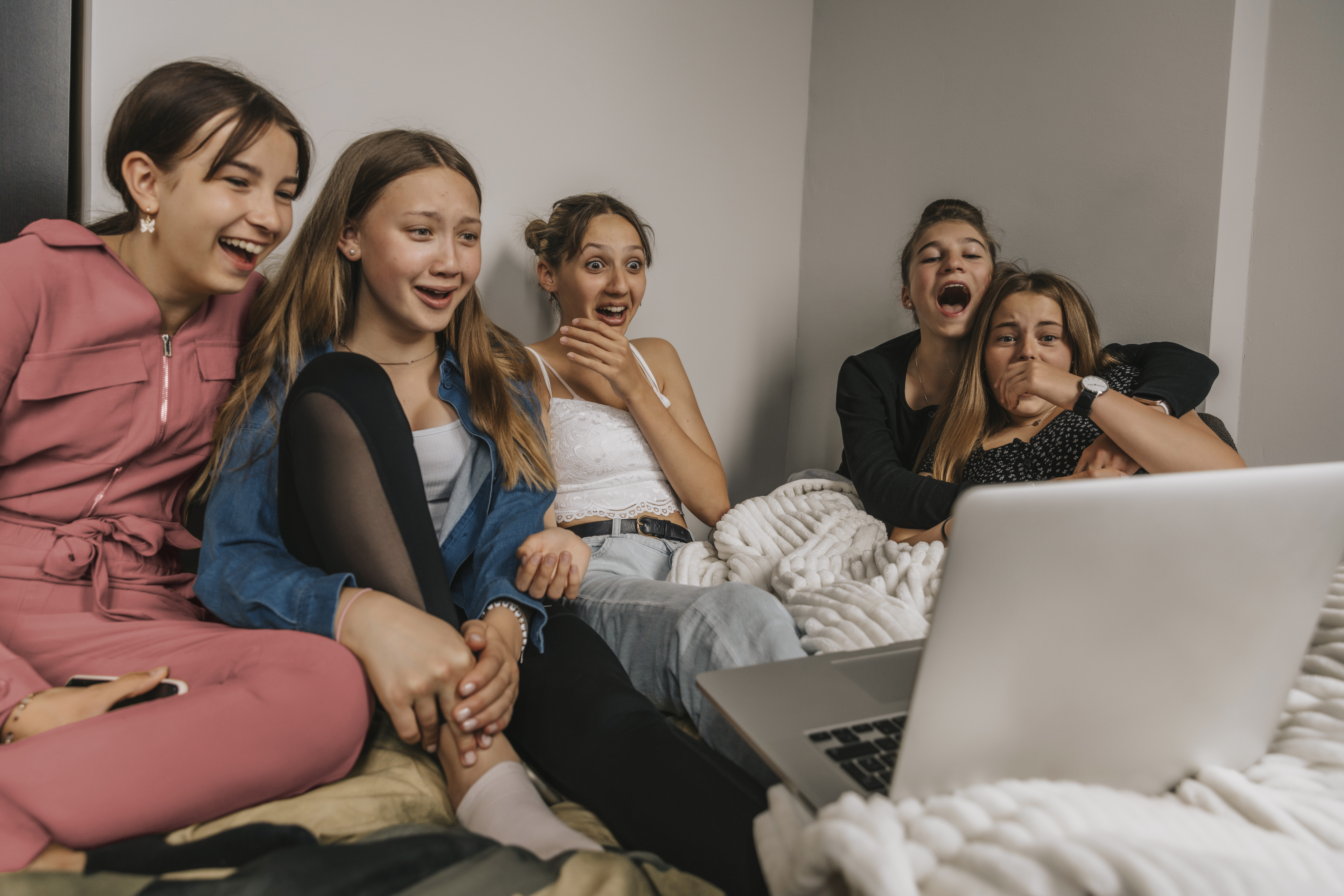 Teenage girls being shocked by image on laptop screen in bedroom, Wuppertal, NRW, Germany